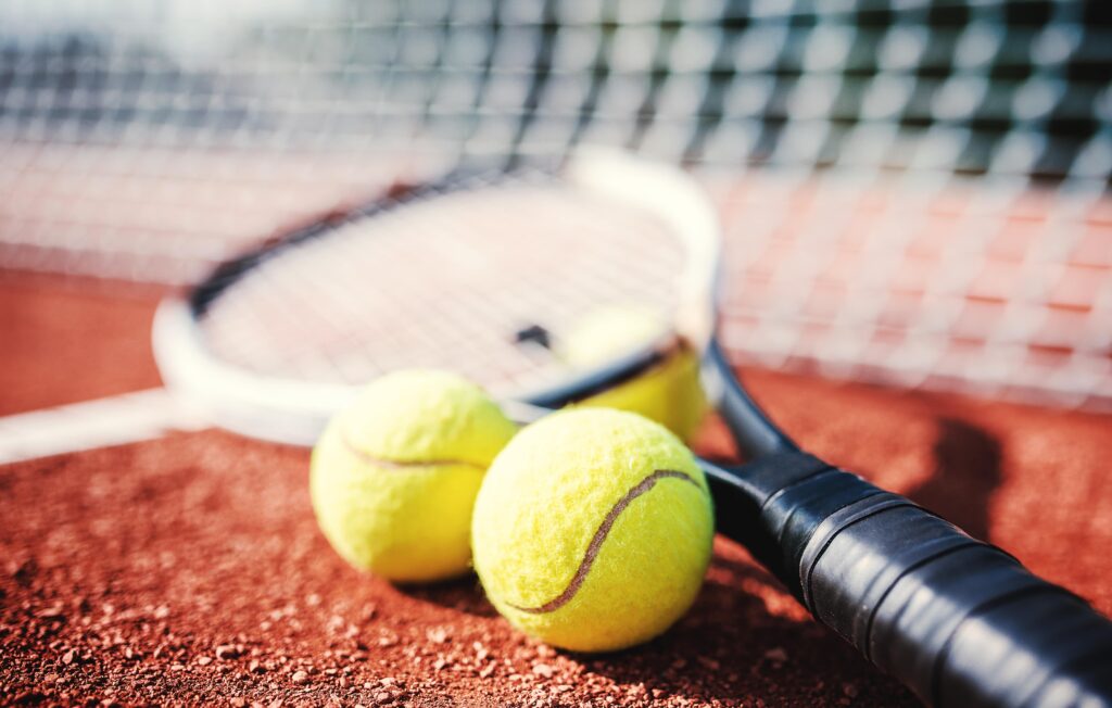 Two tennis balls on the floor with a racket