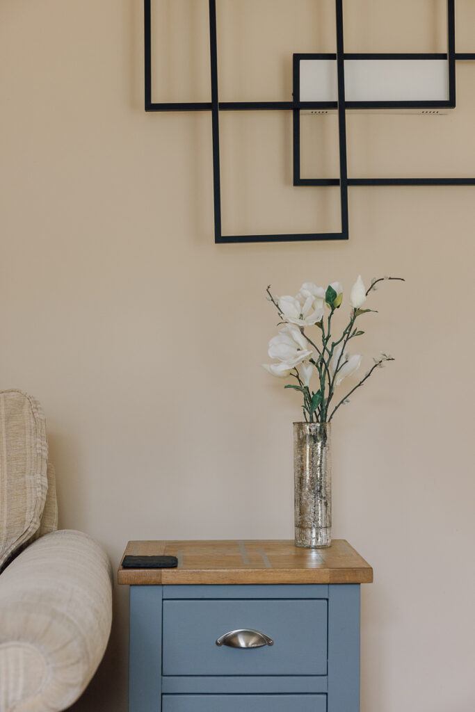 Flower stems in a vase on a side table next to sofa