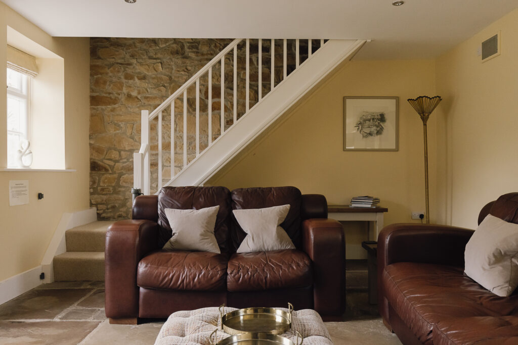 Comfy leather sofa with stairs behind leading upstairs