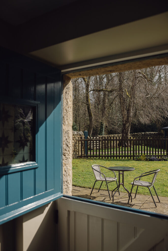 Looking outside from a blue stable door onto a bistro set for two