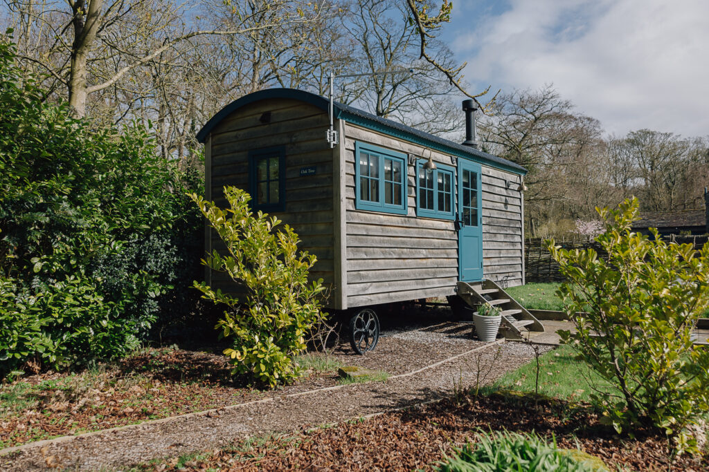 Shepherds hut set in a garden and green brush next to it