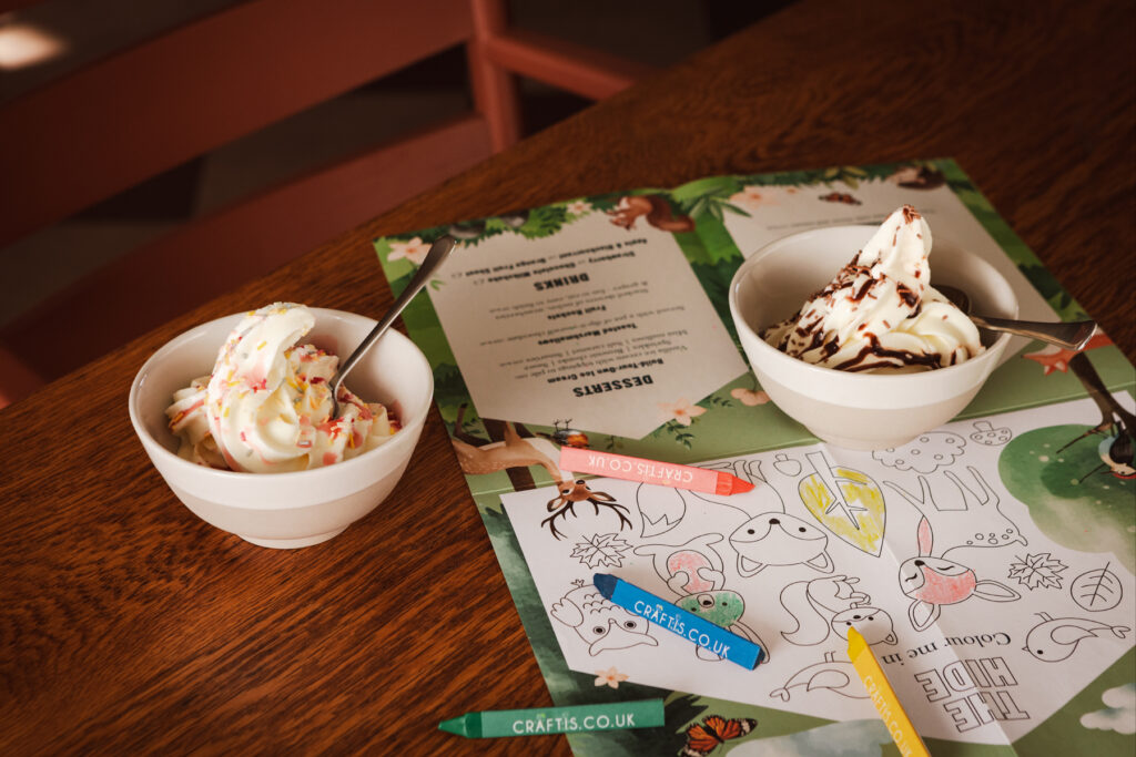 Bowls of ice cream on a table alongside crayons and paper