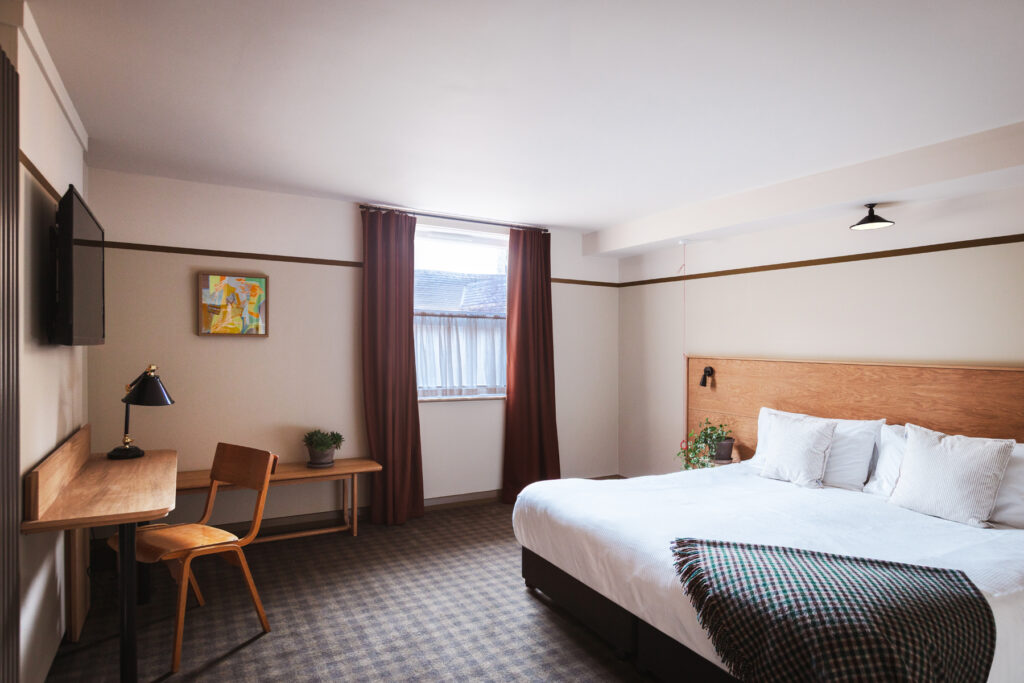 Spacious room with wide bed. Desk, window, and TV facing the bed.