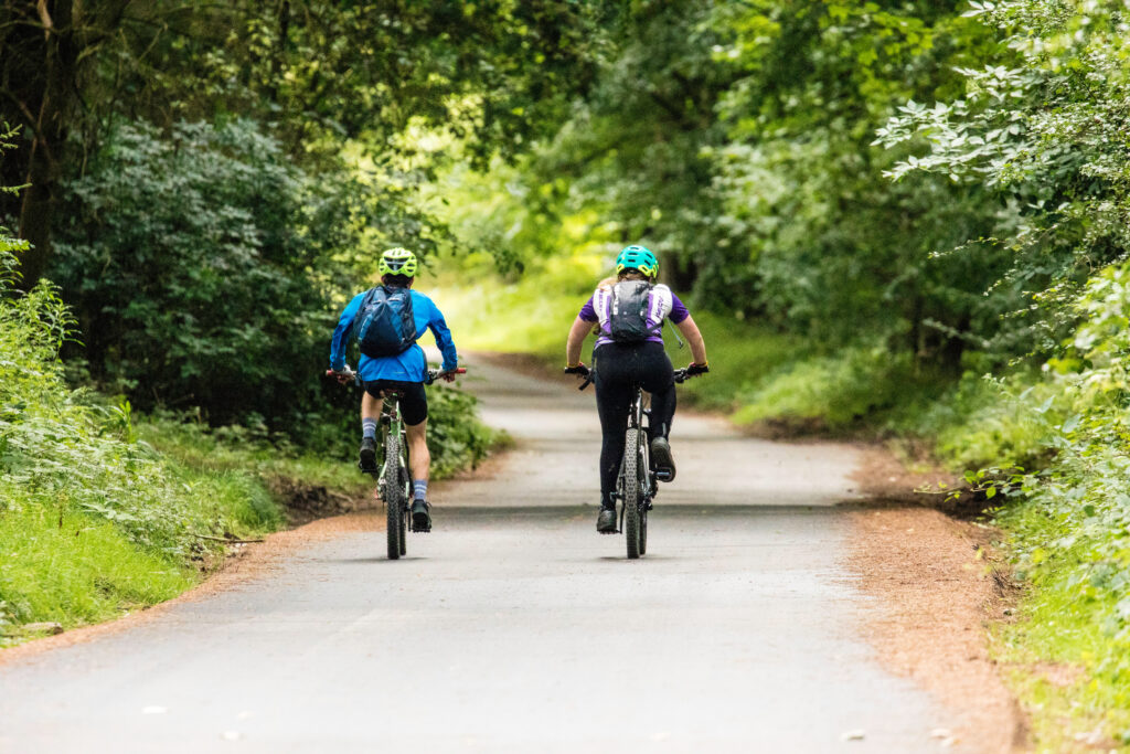 Two mountain biking down a country lane
