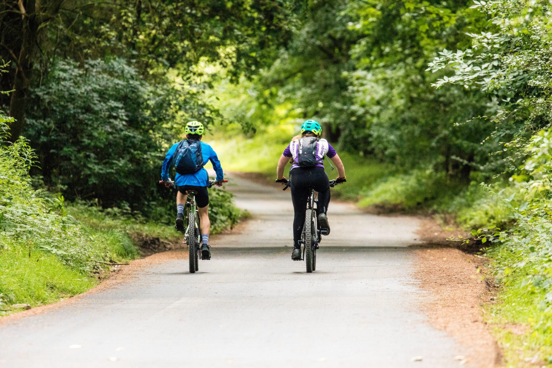 Two mountain biking down a country lane