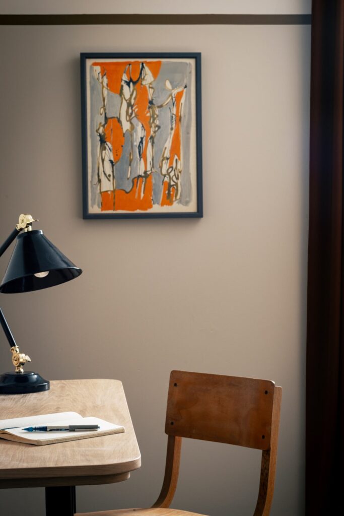 Artwork on a wall with a lamp on a desk