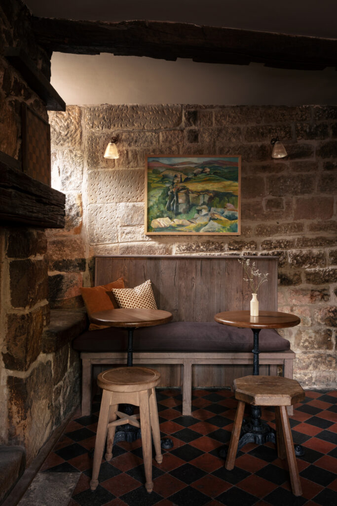 A wooden bench with rust coloured cushions with seating in front.